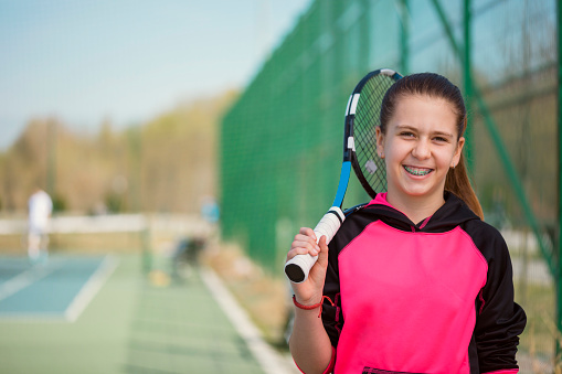 Can you play sport with braces? Girl playing tennis with braces.