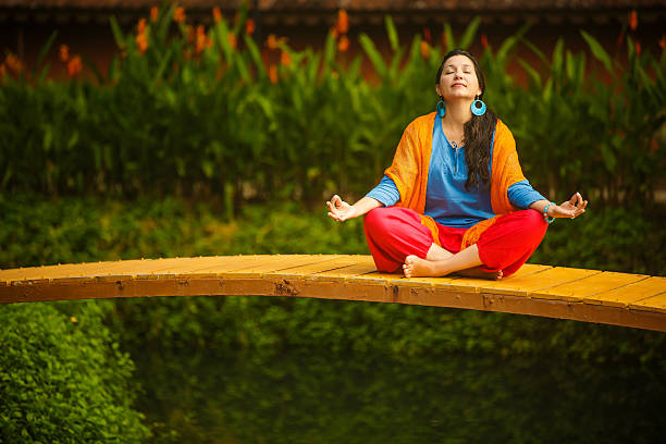 Meditation to overcome fear of braces. Woman meditating on a bridge surrounded by nature.