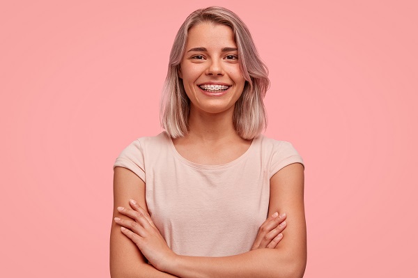 How to Fix an Overbite with Braces, young woman with braces and pink background.
