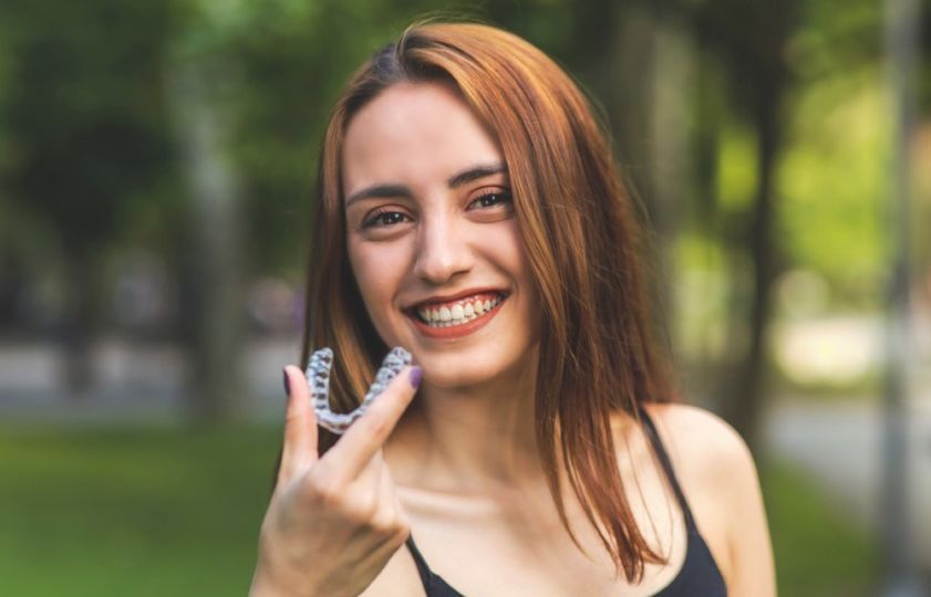 How to fix an overbite with Invisalign, young woman smiling with Invisalign.